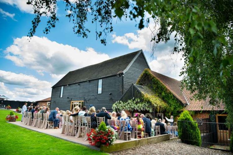 exterior of Crondon Park barn wedding venue in essex as a group of people wait for the happy couple